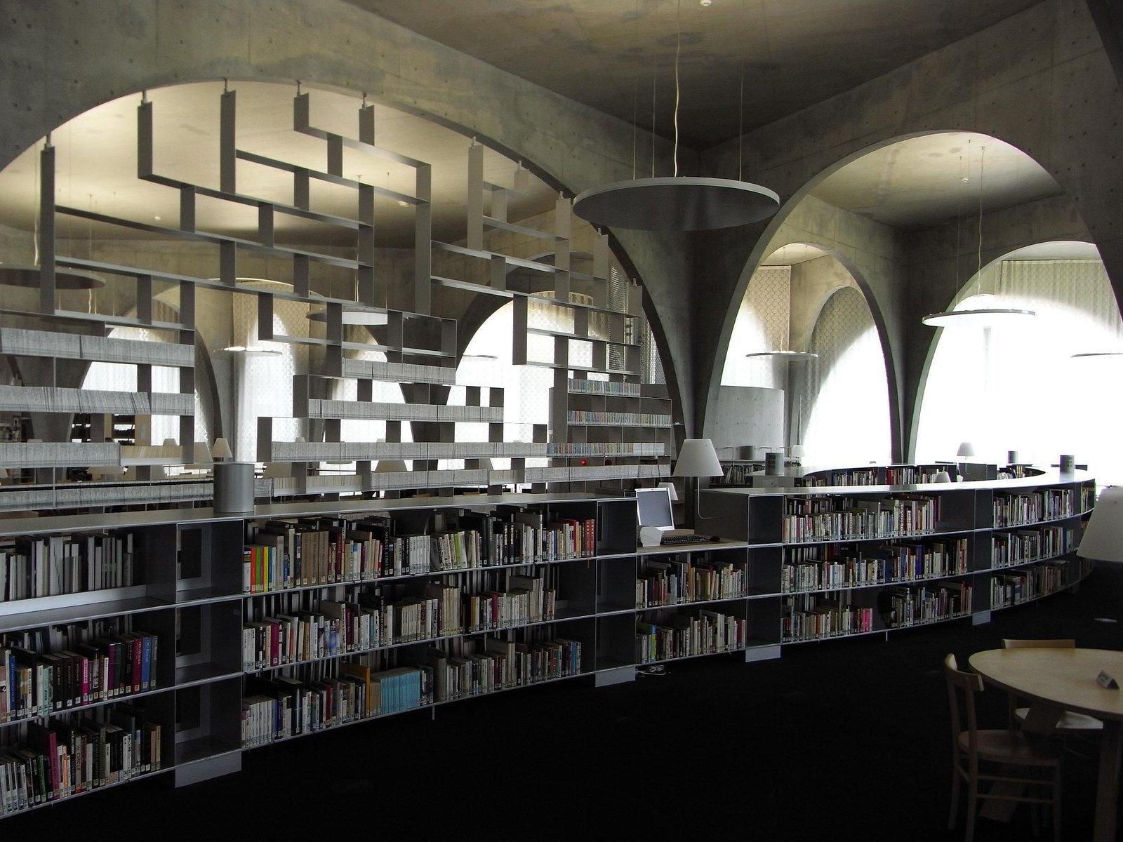 多摩美術大學圖書館閱覽室，寬窄不一的混凝土拱與弧形書架