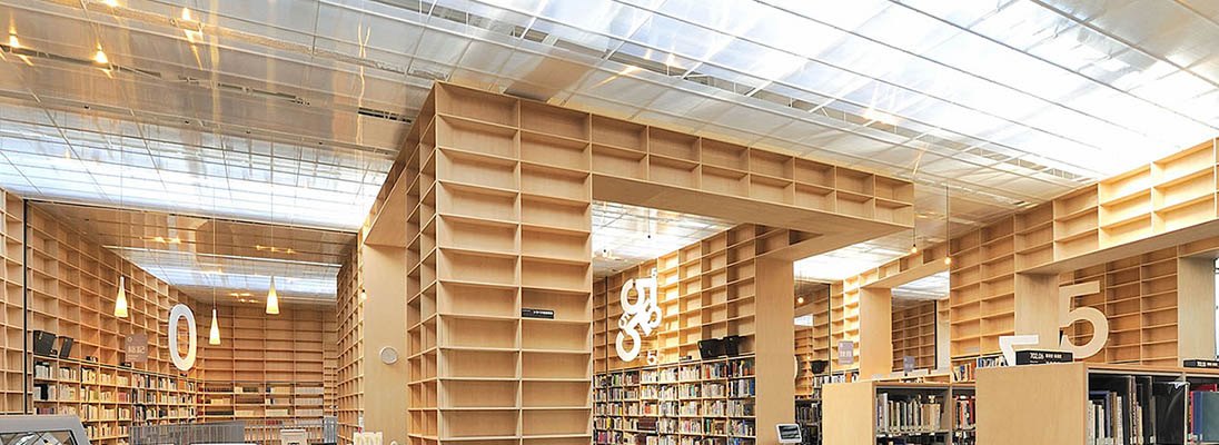 武藏野美術大學圖書館的閱覽空間，整面牆都是木作書架，一路做到天窗下方，架上標著大號分類數字