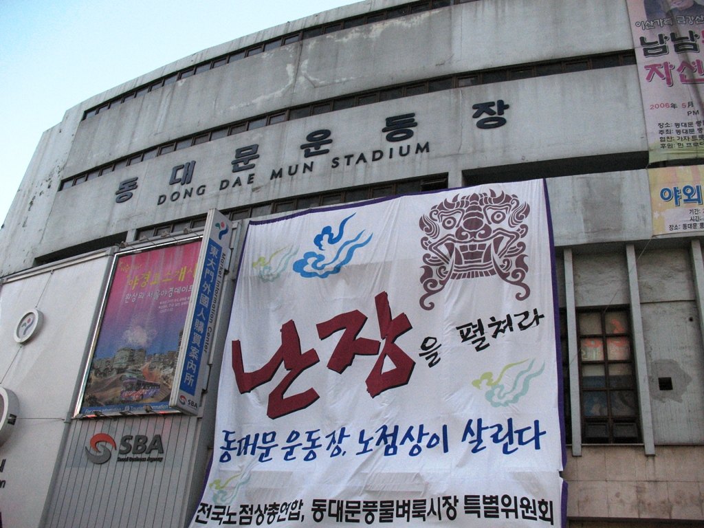2007 年拆除前的東大門運動場正面，牆上掛著攤商團體的抗議布條
